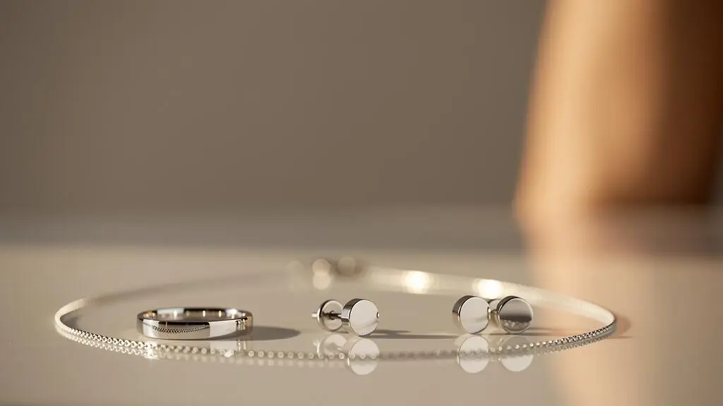 Bijoux en argent rhodié posés en gros plan, reflétant une lumière douce et symbolisant brillance et durabilité